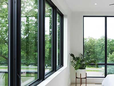 Large and almost floor to ceiling, black-framed Pella windows in a bedroom