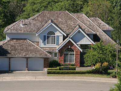 Front view of a large two-story, higher-class home with a brown cedar shake roof