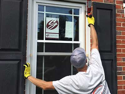 Rebel Exteriors Inc. crew member installing and sealing up a new white Simonton window on a home