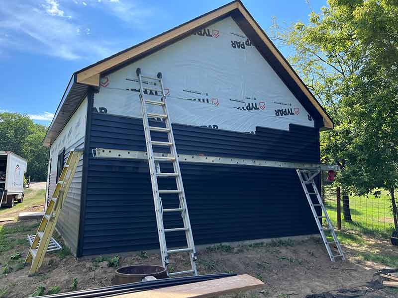 Small residential building in the process of getting new blue siding installed by Rebel Exteriors Inc.